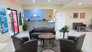 A lobby with a Days Inn sign, a reception desk, brown leather sofas, a round coffee table, and a patterned rug. - Days Inn by Wyndham Near Seaworld San Antonio (San Antonio)