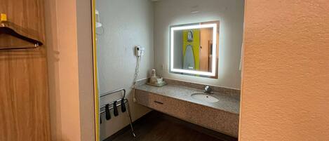 Un baño con lavabo, espejo y toallero.