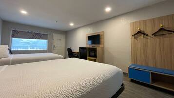 A hotel room with two beds, a TV, a desk, and a wardrobe.
