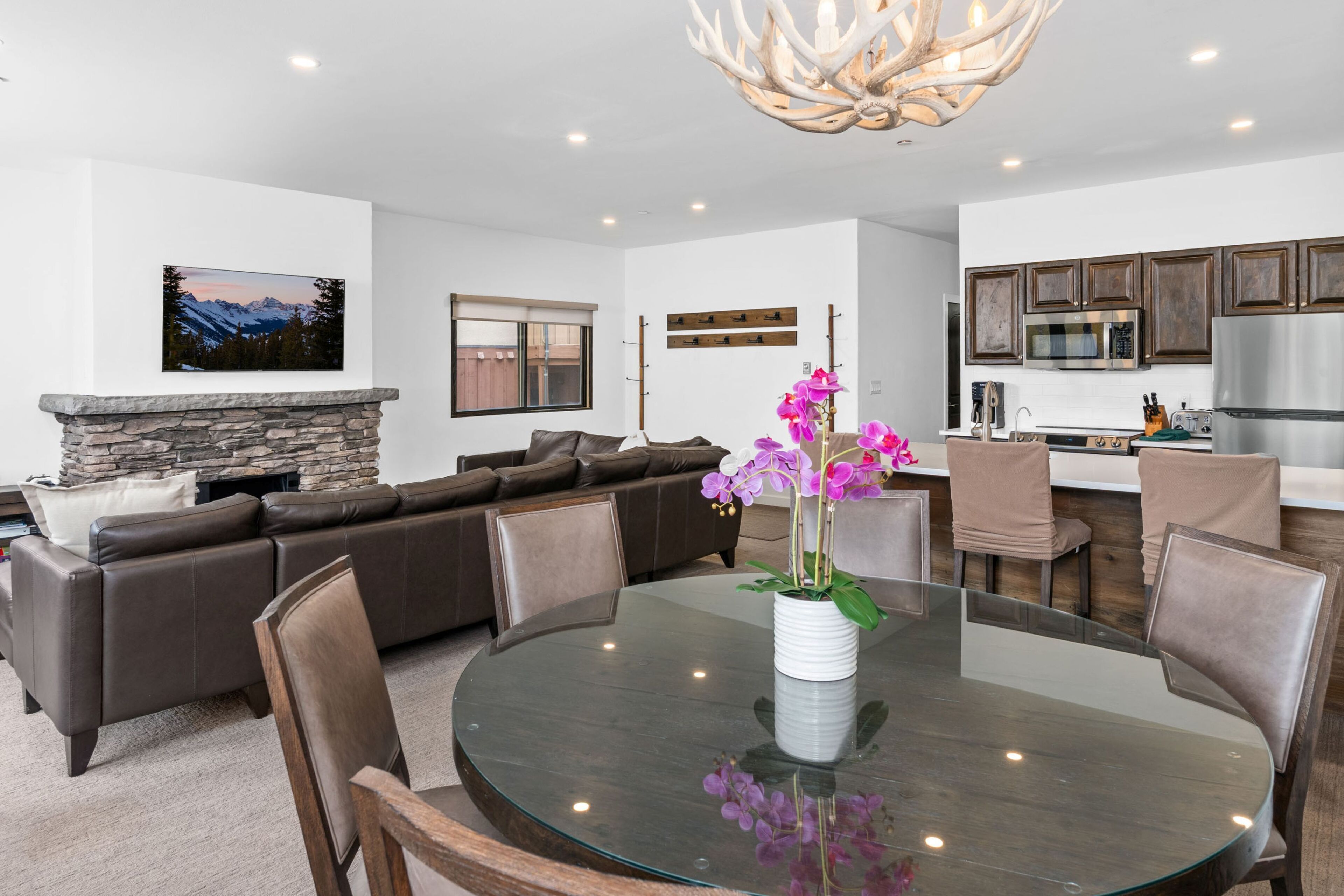 A modern living room with a stone fireplace, a large sofa, and a dining area with a glass table and chairs.