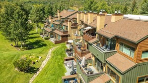 Un quartiere residenziale con case moderne, un prato curato e un paesaggio collinare sullo sfondo.