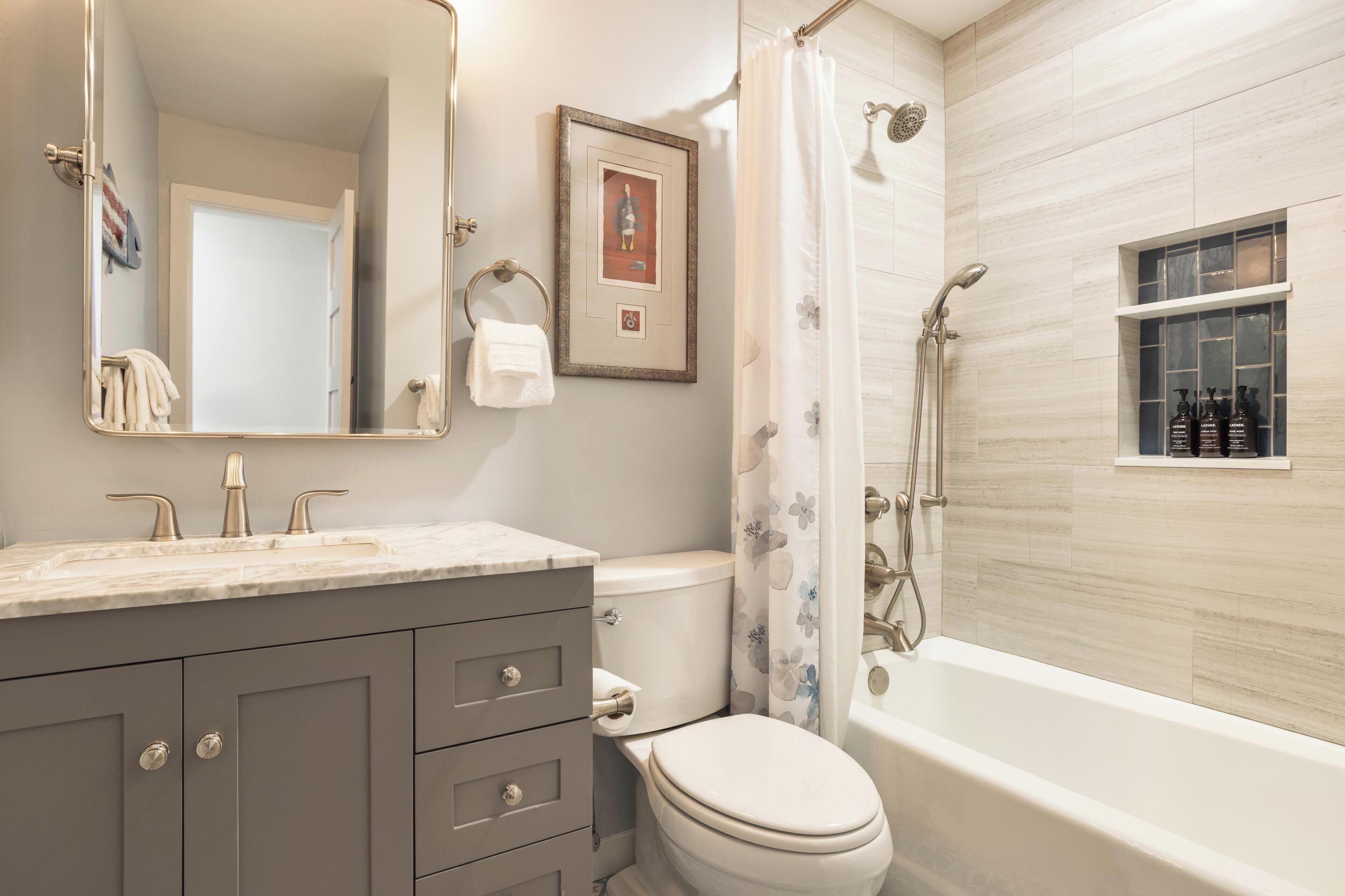 A bathroom with a marble vanity, a toilet, a shower with a glass enclosure, and a framed picture on the wall.