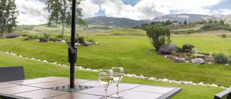 Un patio exterior con una mesa, dos copas de vino y una sombrilla.