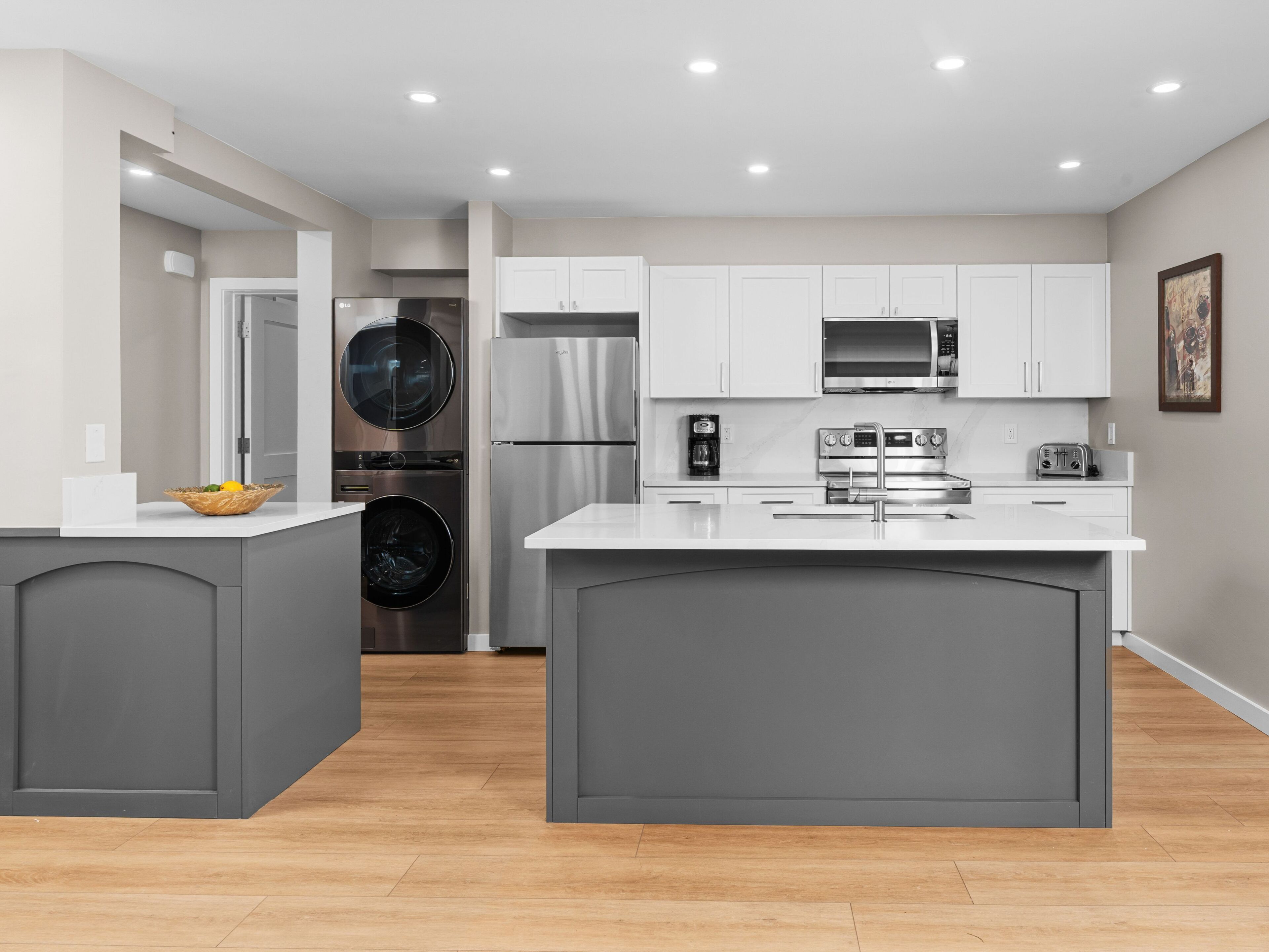 A modern kitchen with grey cabinetry, stainless steel appliances, and a central island.