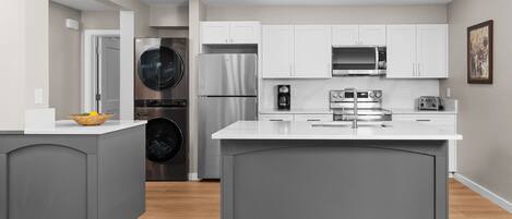 A modern kitchen with grey cabinetry, stainless steel appliances, and a central island.
