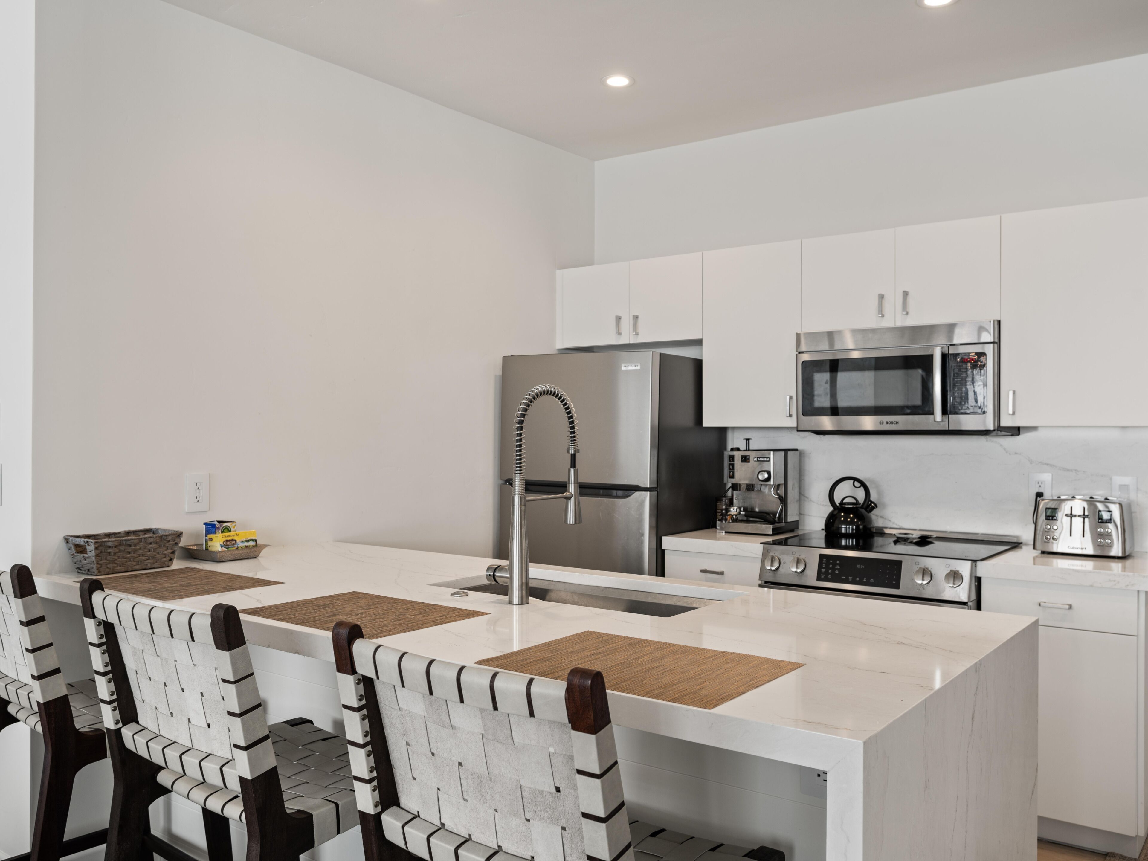 A modern kitchen with white cabinets, stainless steel appliances, and a central island with a sink.