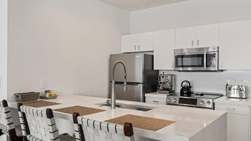 A modern kitchen with white cabinets, stainless steel appliances, and a central island with a sink.