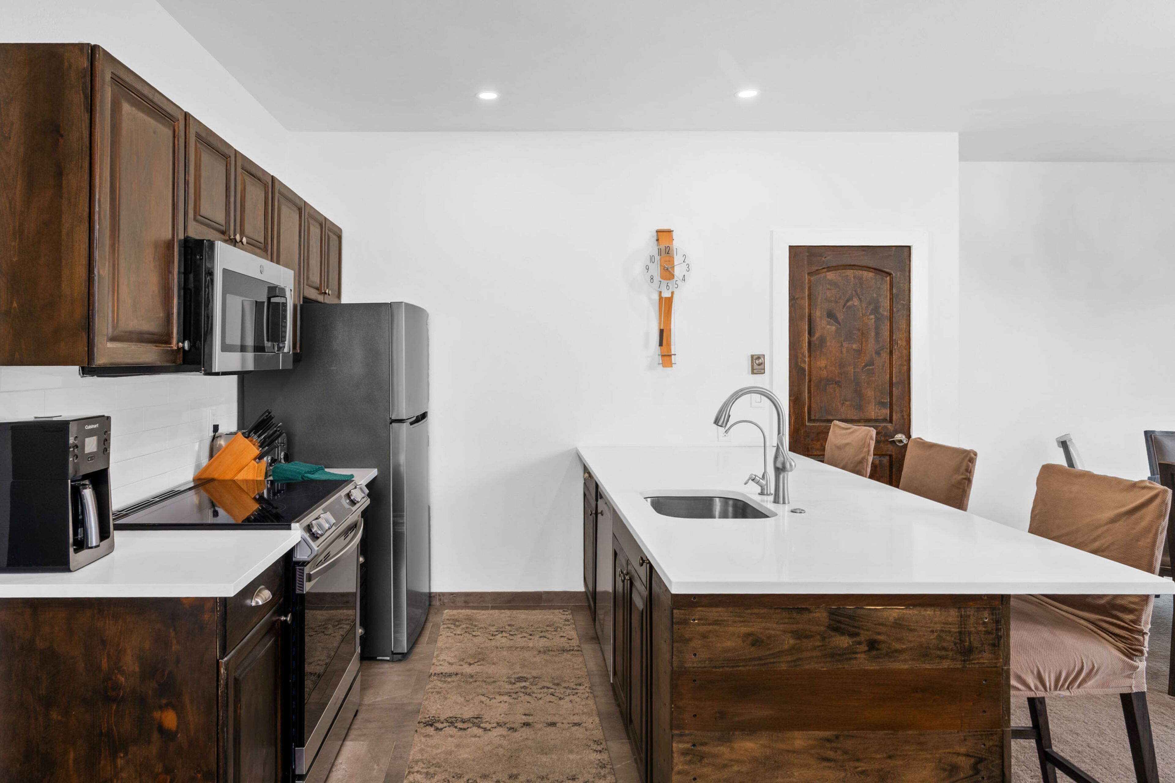 Une cuisine moderne dotée d’un îlot central, d’appareils électroménagers en acier inoxydable et de meubles de rangement en bois.