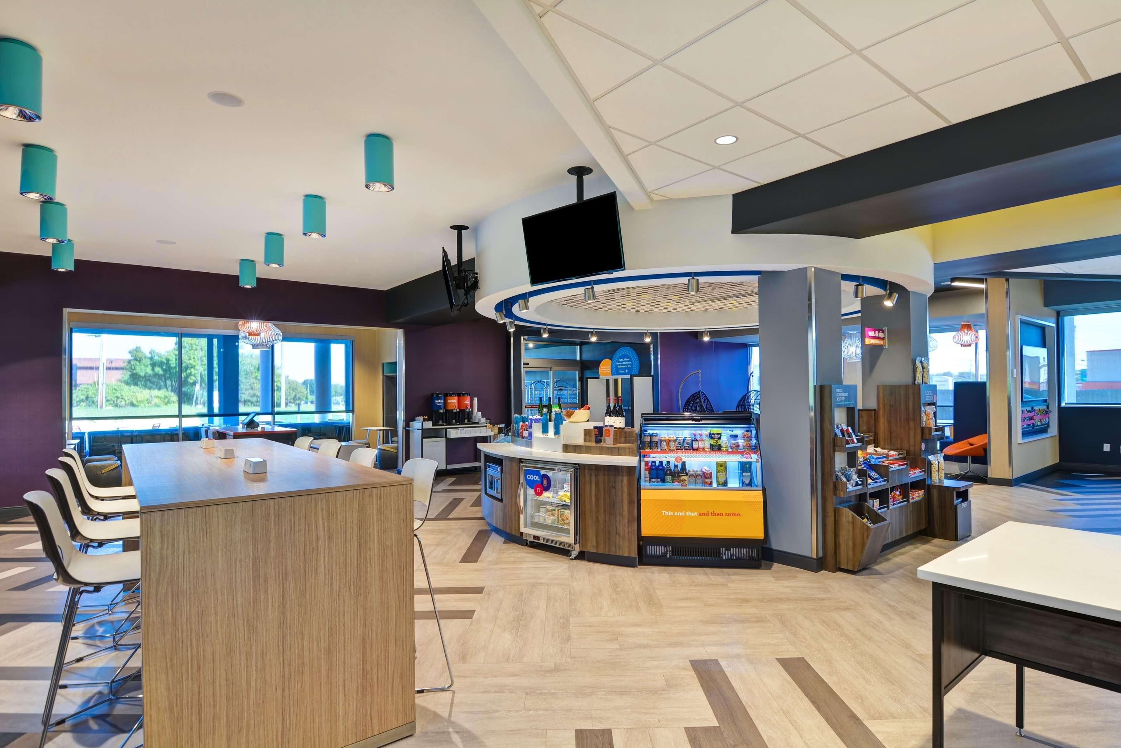A modern indoor space with a central counter, seating area, and a large window providing natural light.