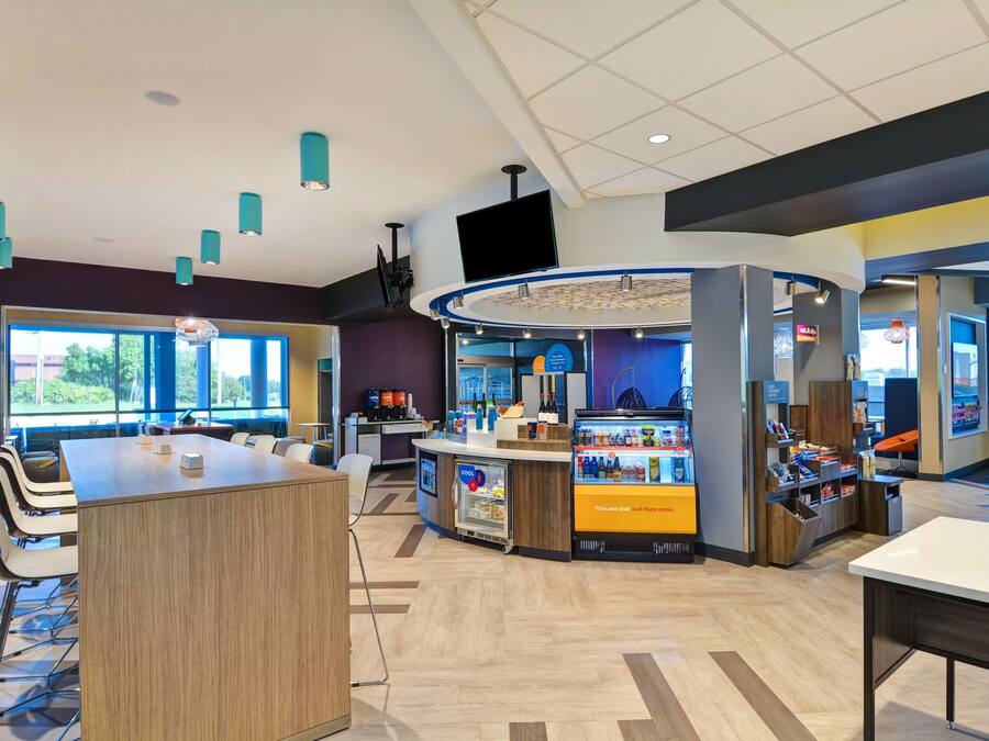 A modern indoor space with a central counter, seating area, and a large window providing natural light.