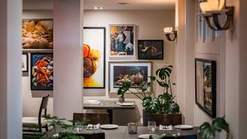 A dining area with a table set for two, surrounded by framed artwork on the walls.