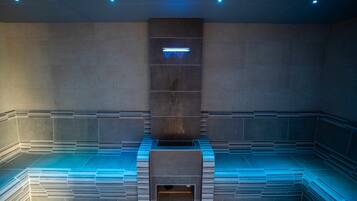 A modern, minimalist sauna with a geometric design, featuring a central bench and a light fixture above.