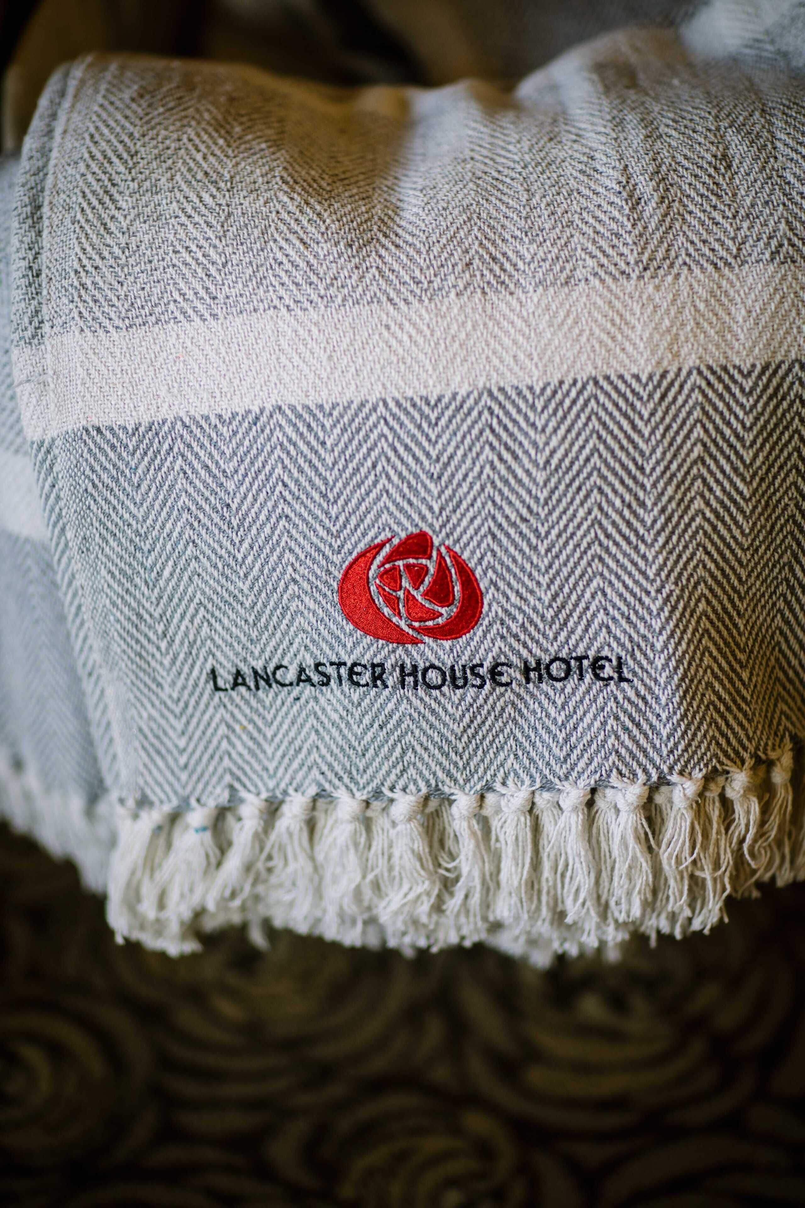 A textured fabric with a herringbone pattern and a logo with the text 'Lancaster House Hotel'.