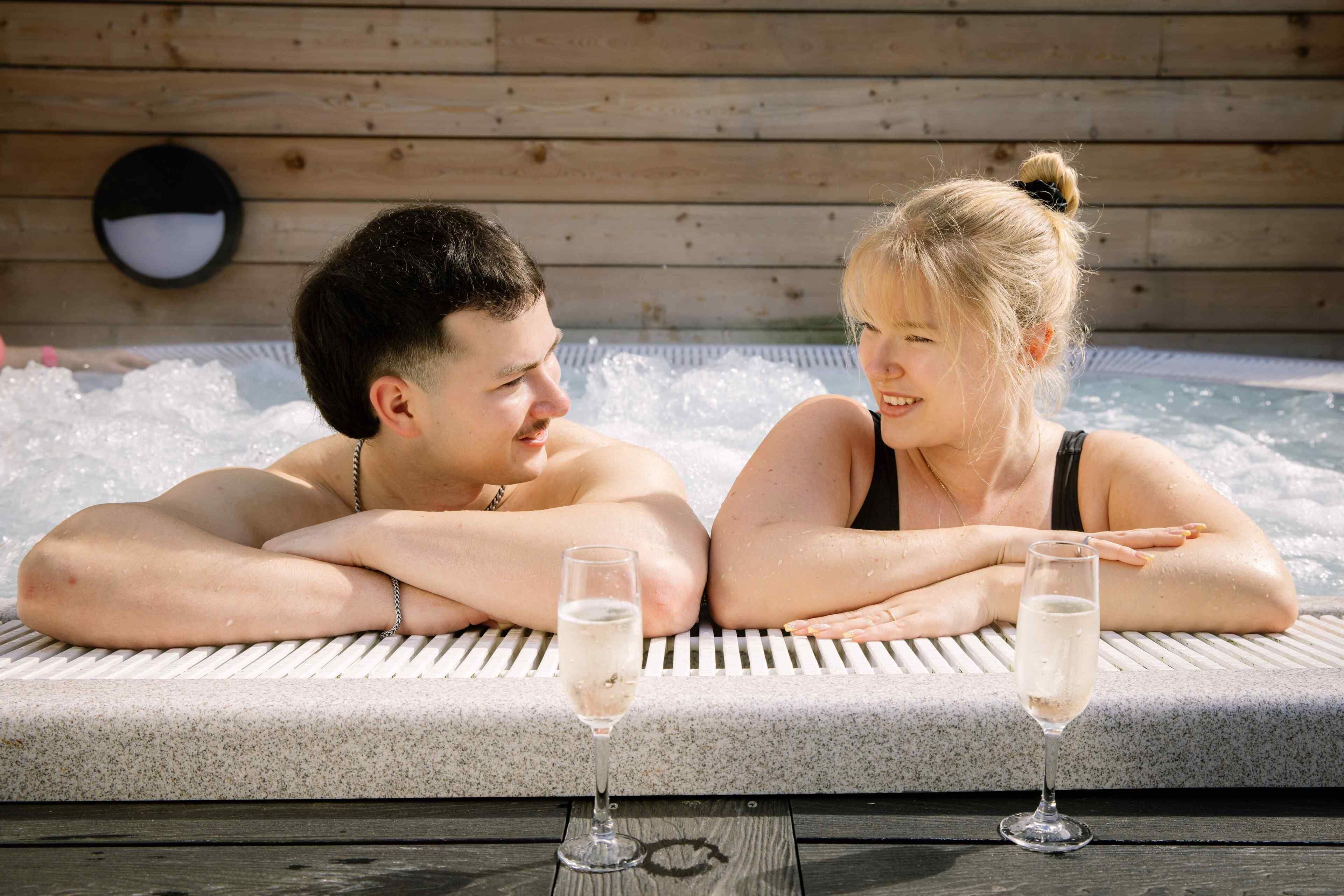 Two people relaxing in a hot tub with champagne glasses.