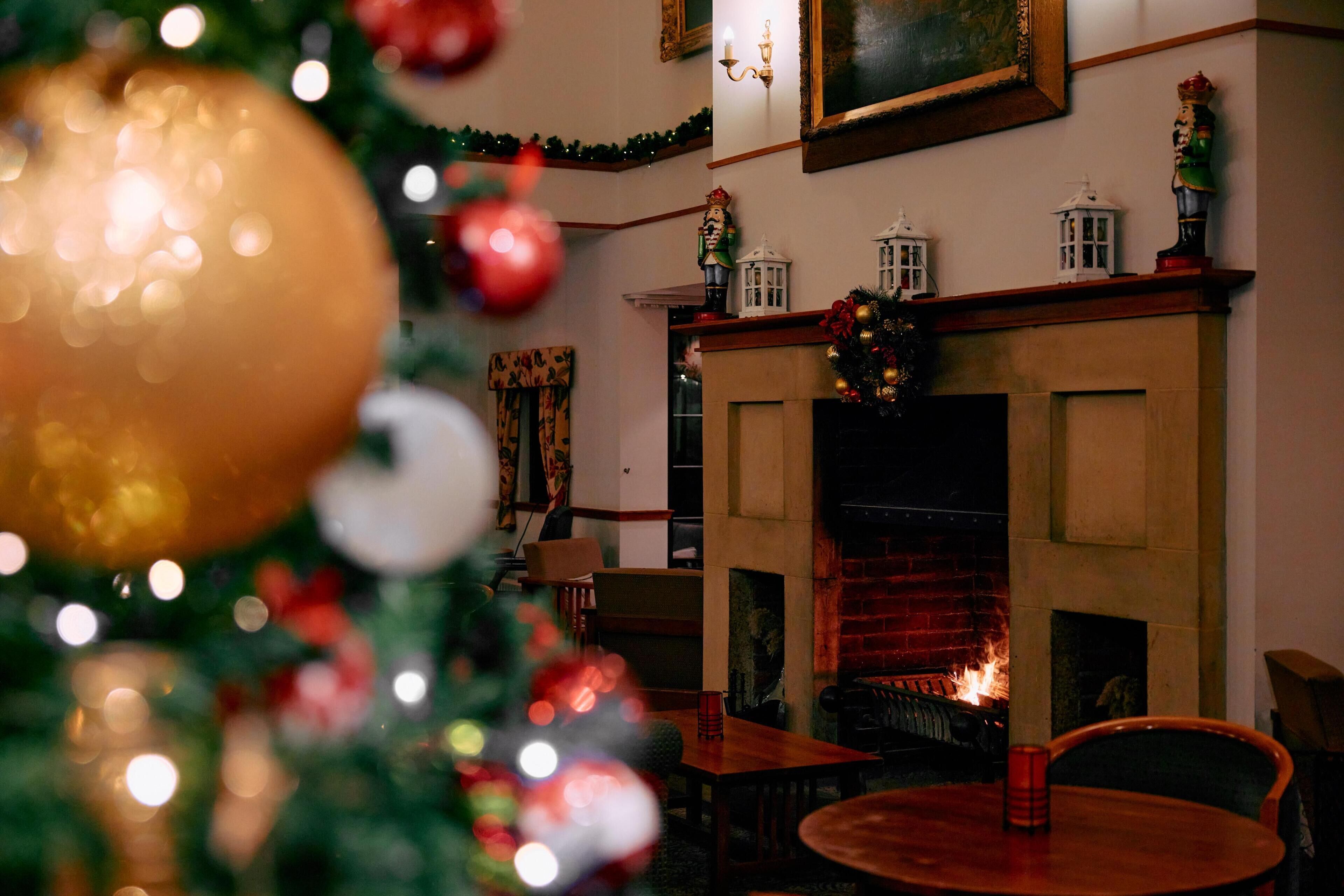 Une pièce avec une cheminée, un sapin de Noël et un coin repas.