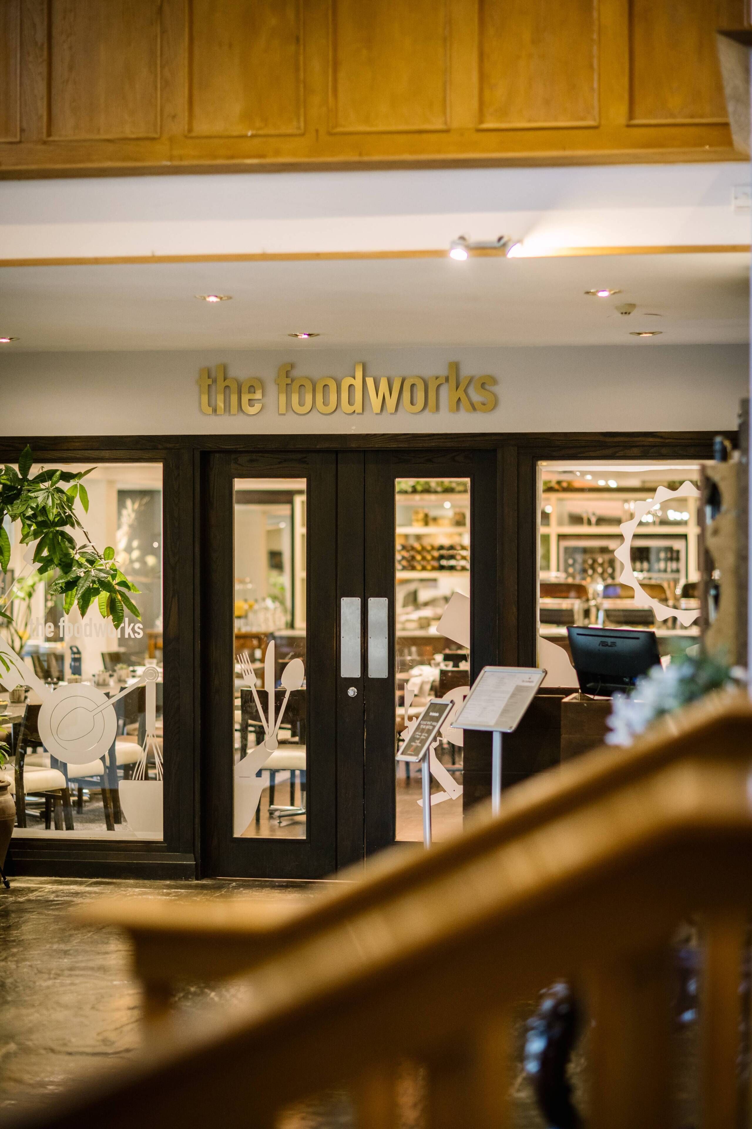 A restaurant entrance with a sign reading 'the foodworks' and a view of the interior through the glass doors.