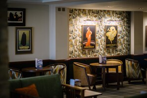 Ein Restaurantinnenraum mit Tischen, Stühlen und Bildern an der Wand.