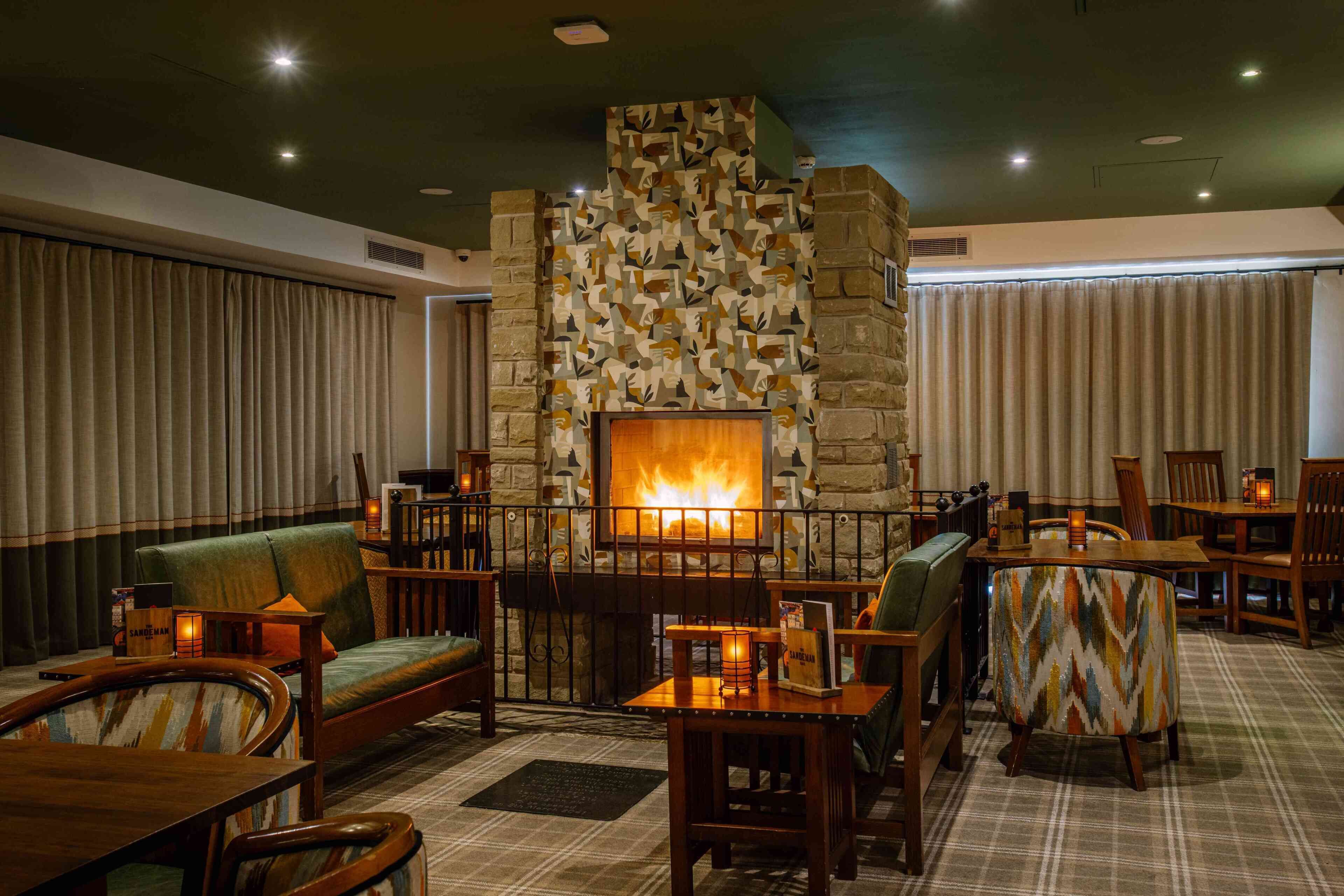 A cozy lounge area with a stone fireplace, comfortable seating, and a plaid-patterned rug.