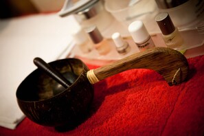 A wooden spoon resting on a red surface, with various bottles and containers in the background.