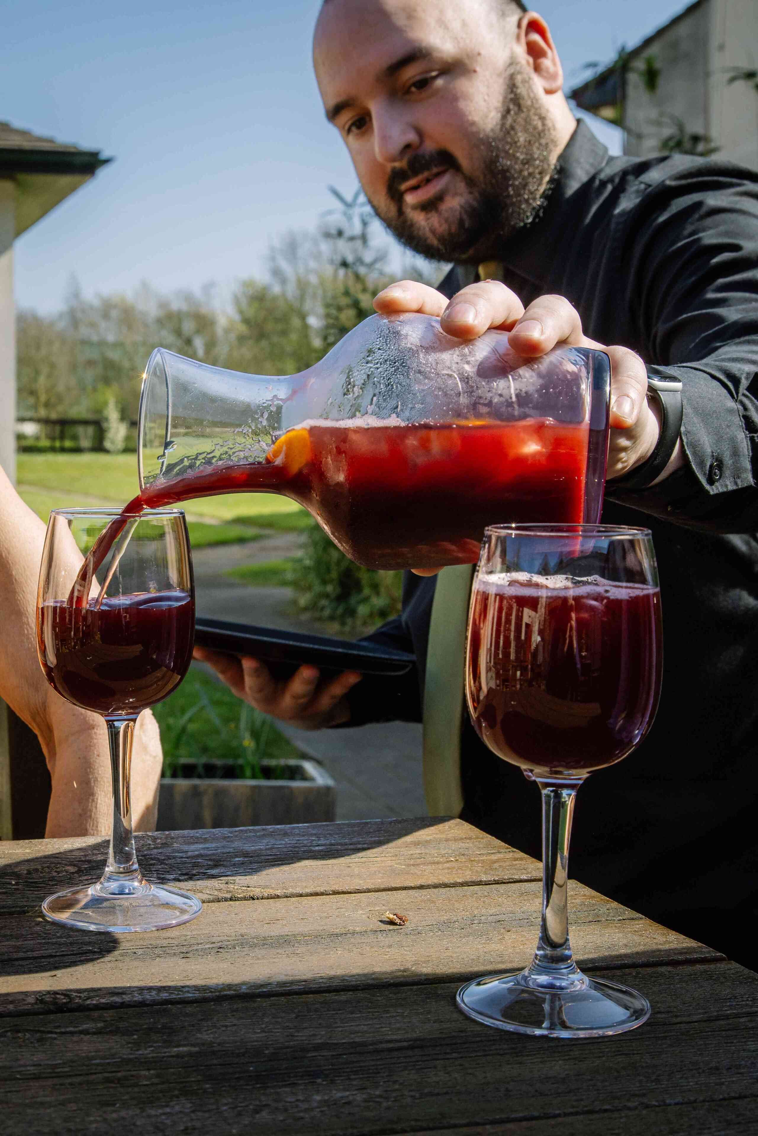 A person pouring a red liquid from a bottle into a glass.