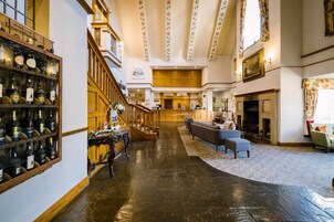 Eine Hotelhalle mit Treppe, einer Rezeption, einer Sitzecke und einer Weinausstellung.