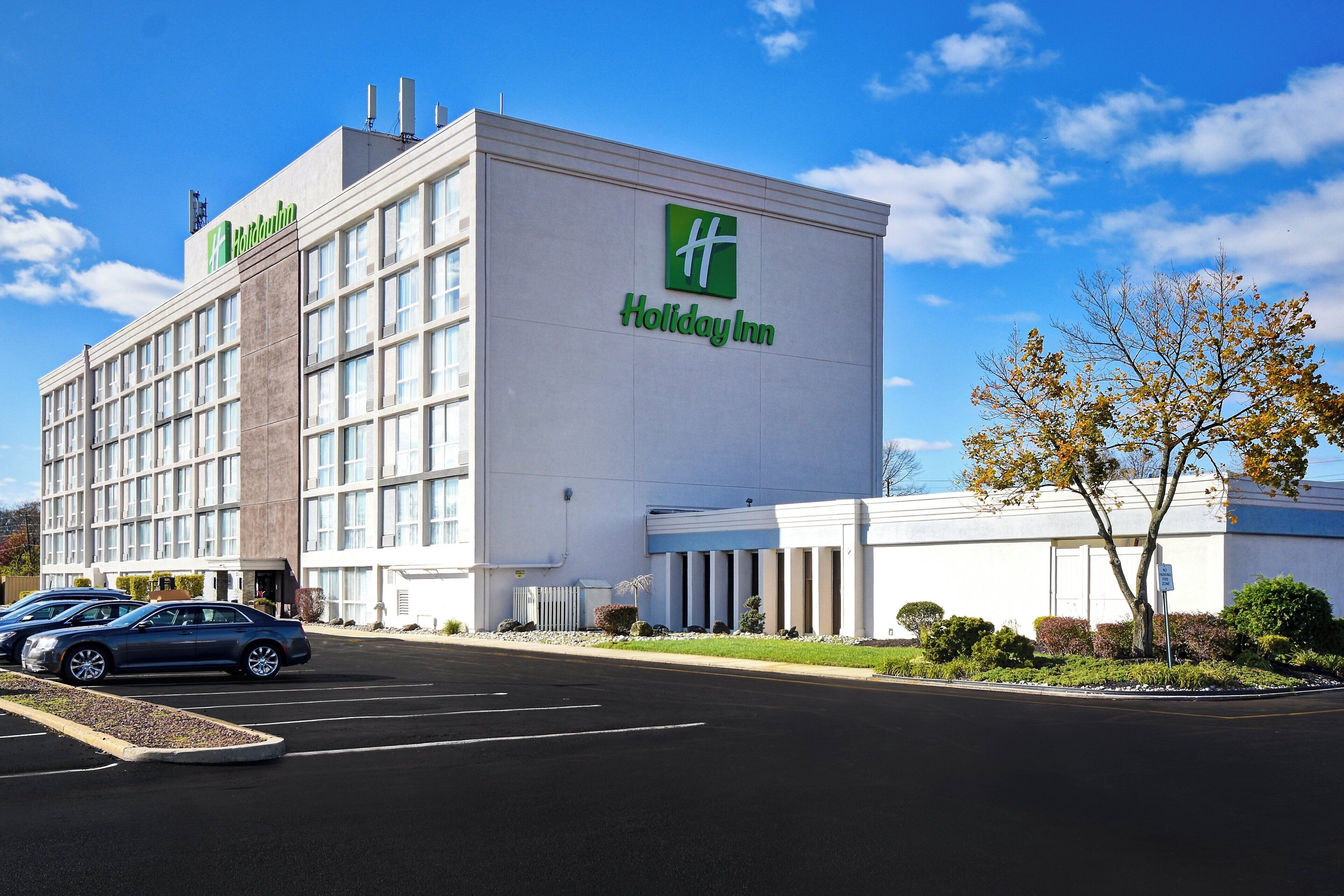 A Holiday Inn hotel with a large parking lot and a clear blue sky.