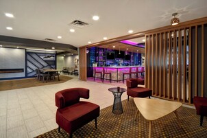 Un área de bar moderna con mostrador, asientos y techo decorativo.
