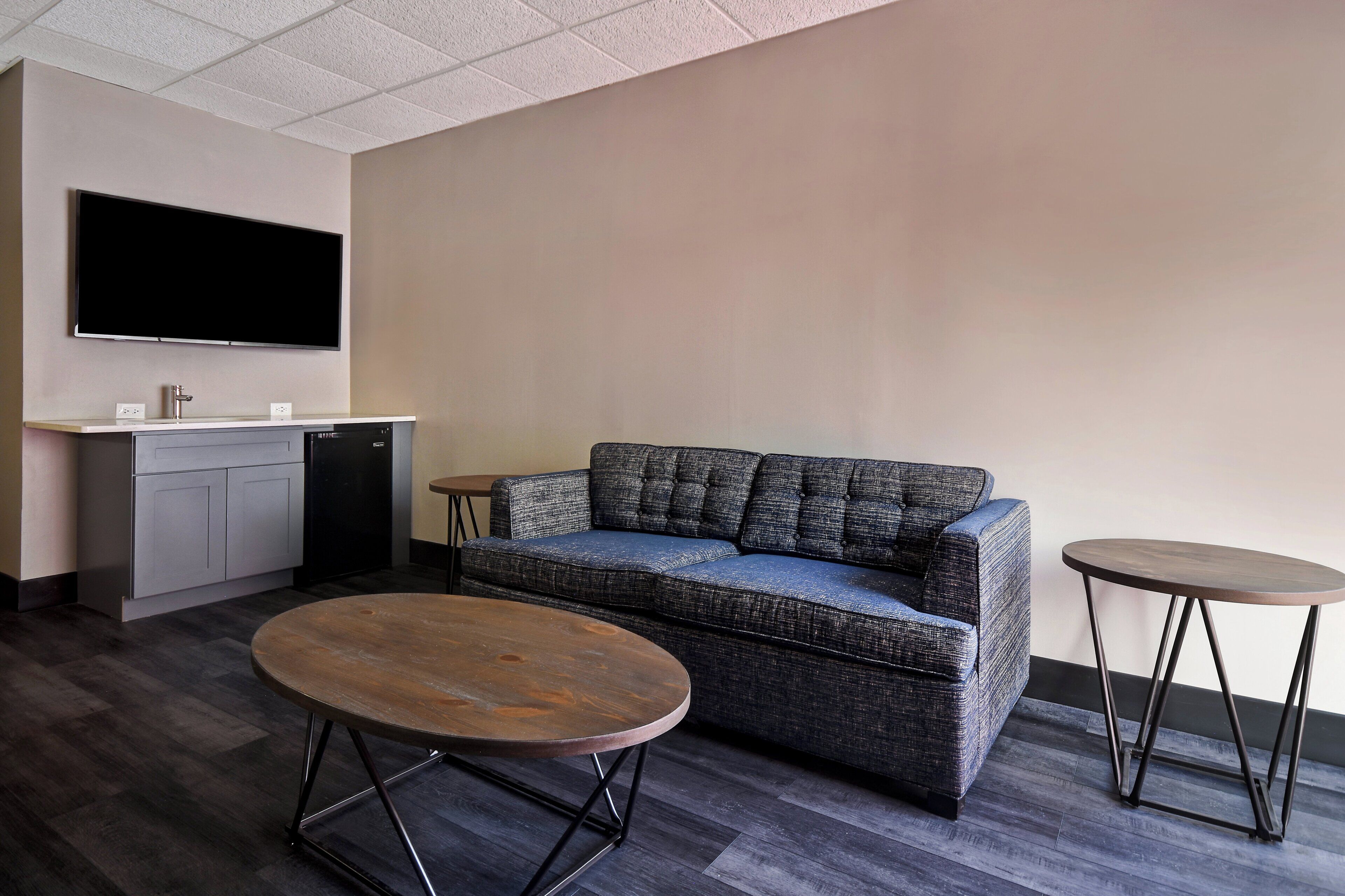 A modern living room with a sofa, a coffee table, a TV, and a kitchenette.