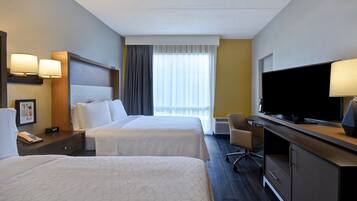 A hotel room with two beds, a TV, a desk, and a chair.