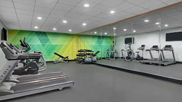 Un gimnasio con cintas de correr, elípticas y pelotas de ejercicio.