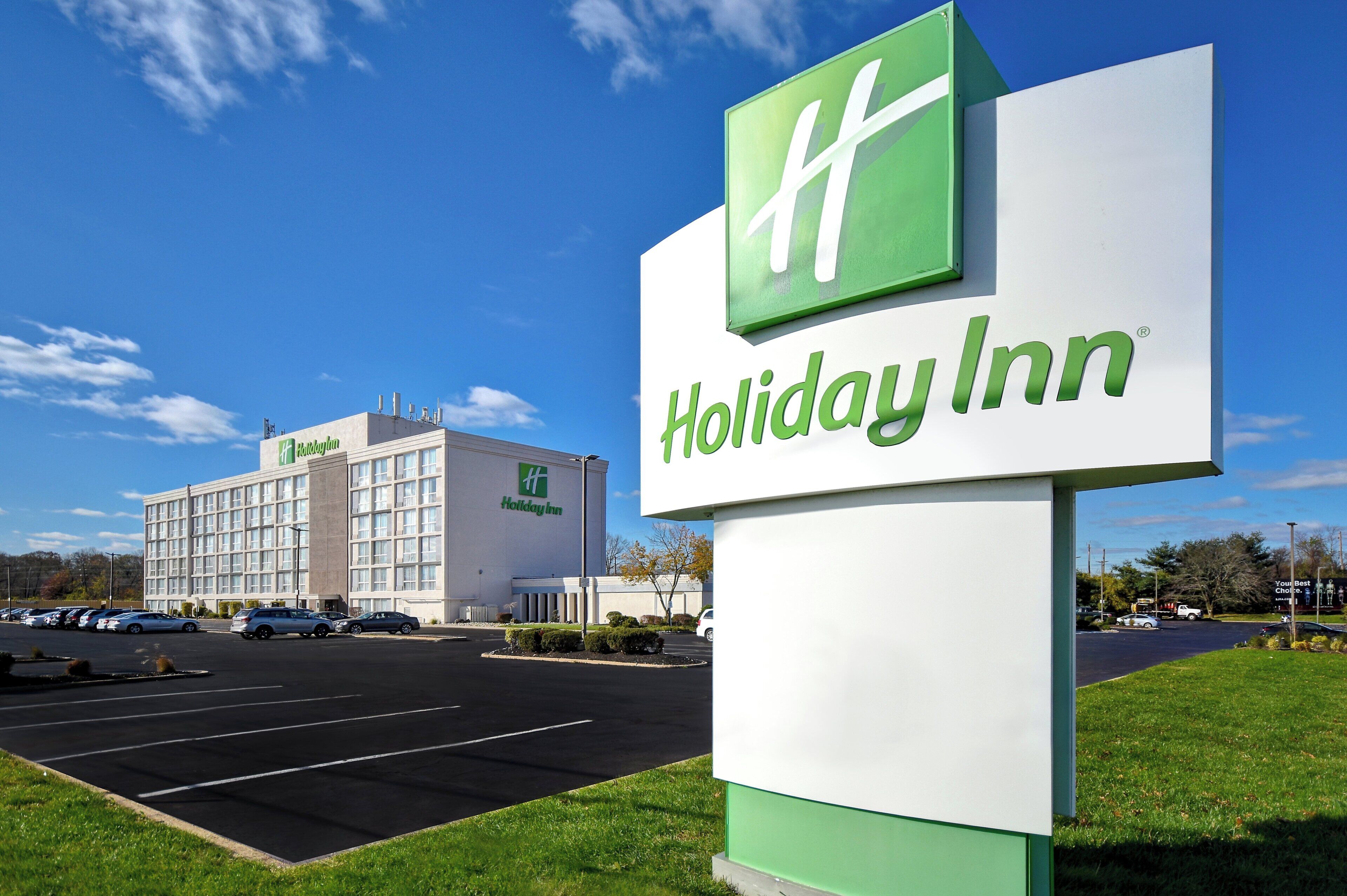A Holiday Inn sign with a large building in the background.