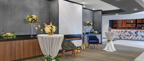 A hotel lobby with a reception desk, seating area, and a bar.