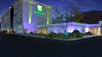 Un hotel Holiday Inn con fachada moderna, amplios ventanales y una entrada bien iluminada.