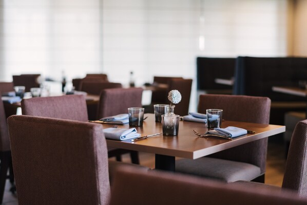 A restaurant with multiple tables, each set with cutlery, glasses, and a centerpiece. - Holiday Inn Philadelphia-Cherry Hill by IHG (Cherry Hill)