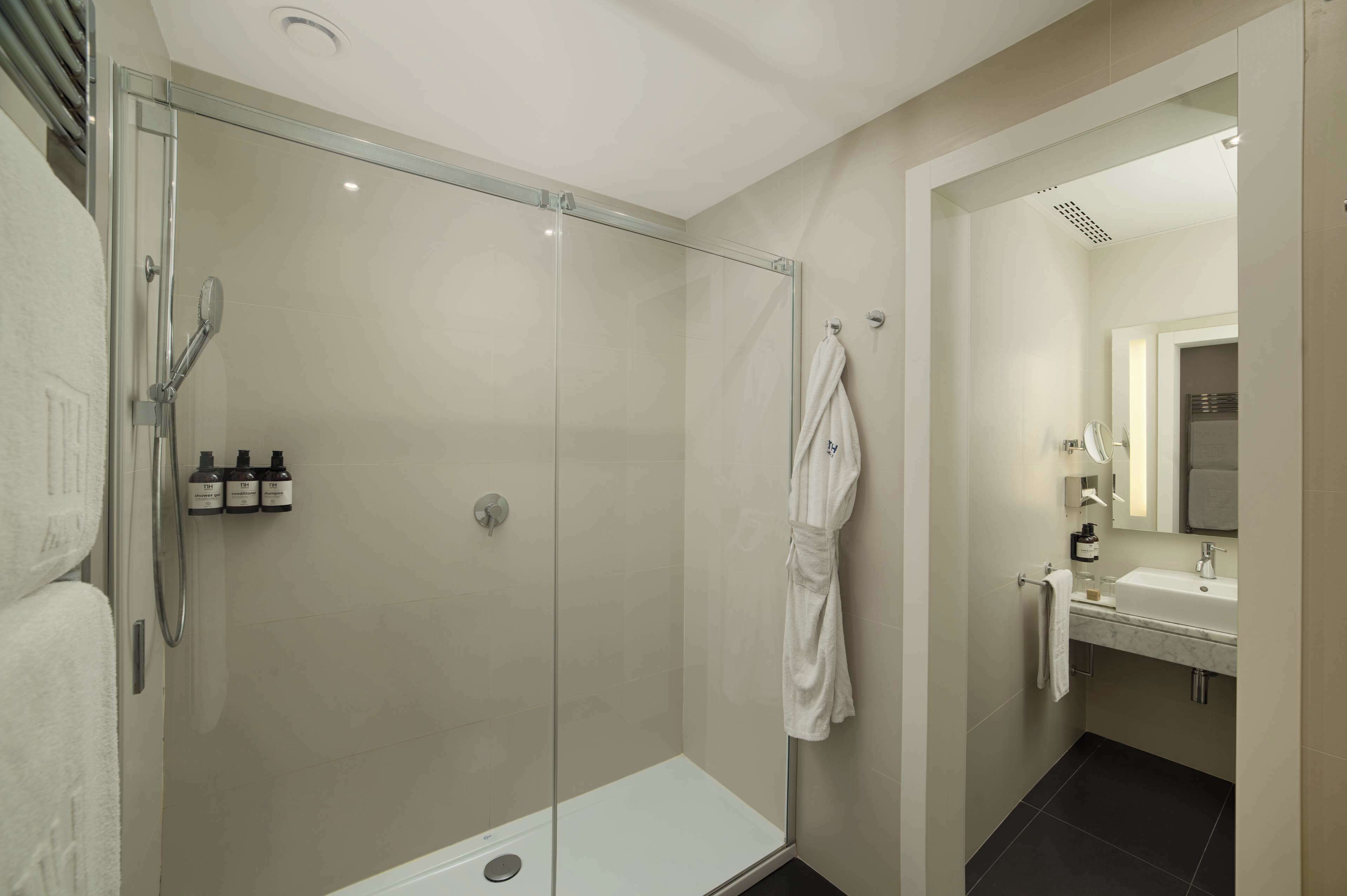 Un baño moderno con ducha envuelta en vidrio, una bañera blanca y un tocador con espejo.