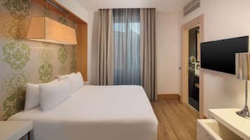 Ein Hotelzimmer mit einem großen Bett, einem Schreibtisch, einem Fernseher und einem Kleiderschrank.