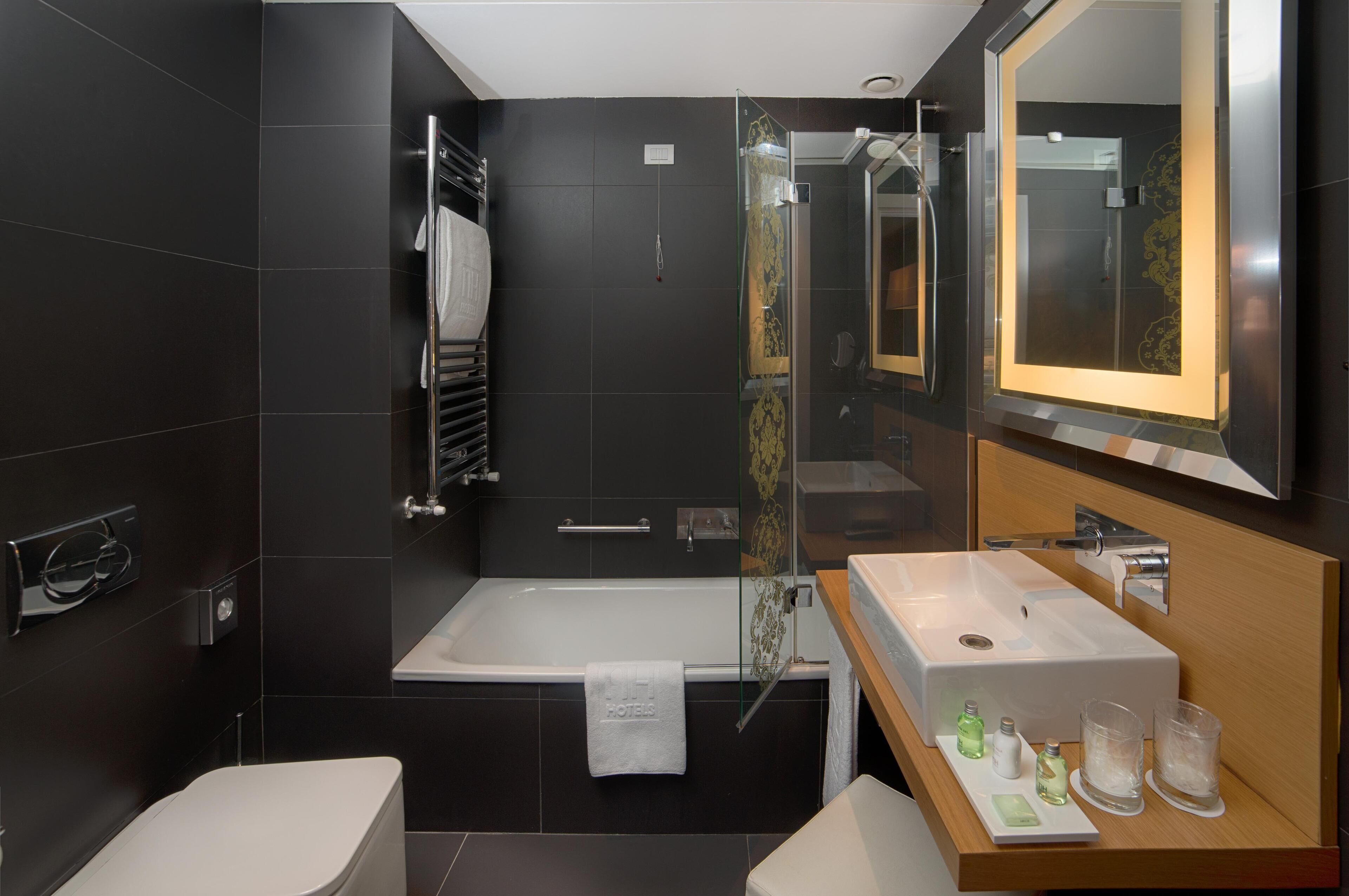 Un baño moderno con una bañera, un espejo grande y un lavabo con artículos de tocador.