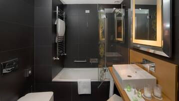 Un bagno moderno con una vasca, uno specchio grande e un mobile lavabo con lavandino e articoli da toilette.