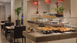 A breakfast buffet with pastries, a coffee station, and potted plants. - NH Genova Centro (Genoa)