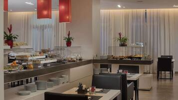A modern restaurant with a buffet setup, including a variety of food items and a seating area with tables and chairs.