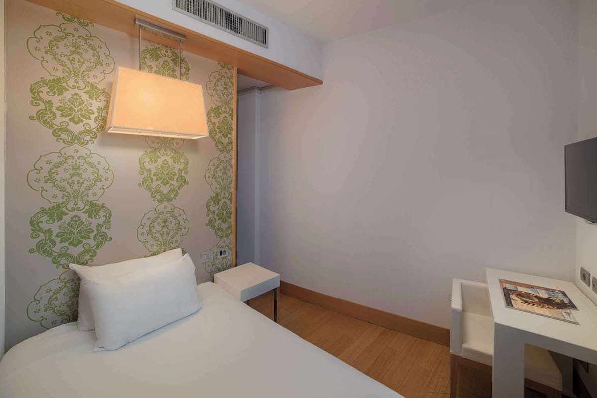Habitación individual estándar | Edredón, minibar, caja de seguridad en la habitación y escritorio