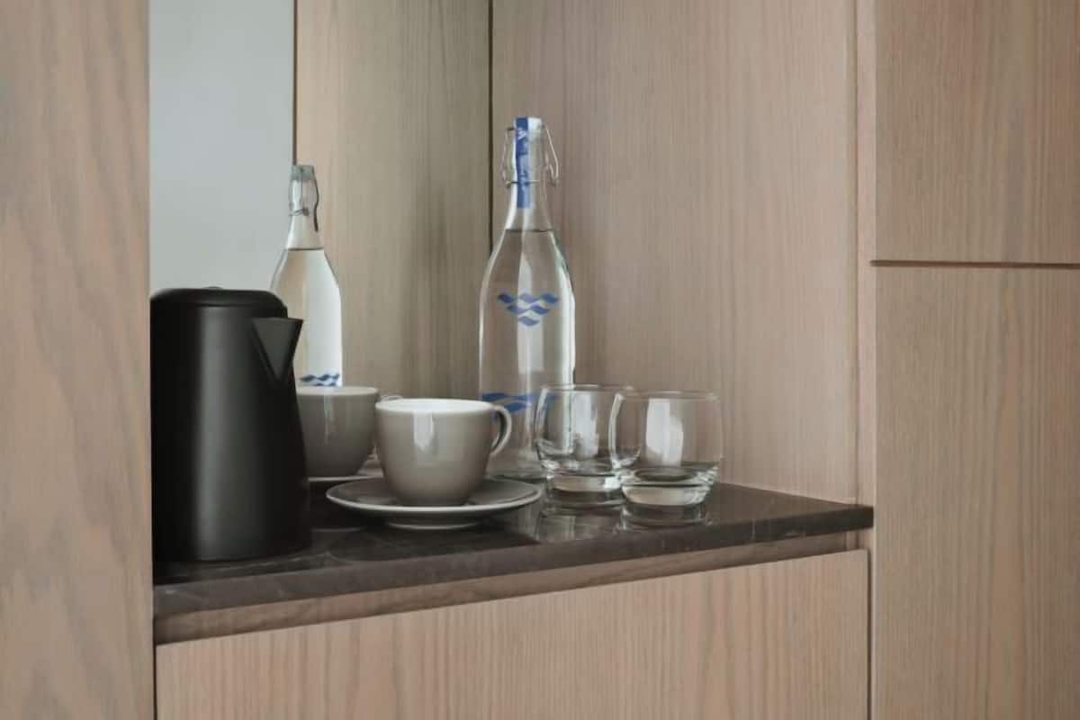 A kitchen counter with a coffee maker, a bottle of water, a cup, and a glass.