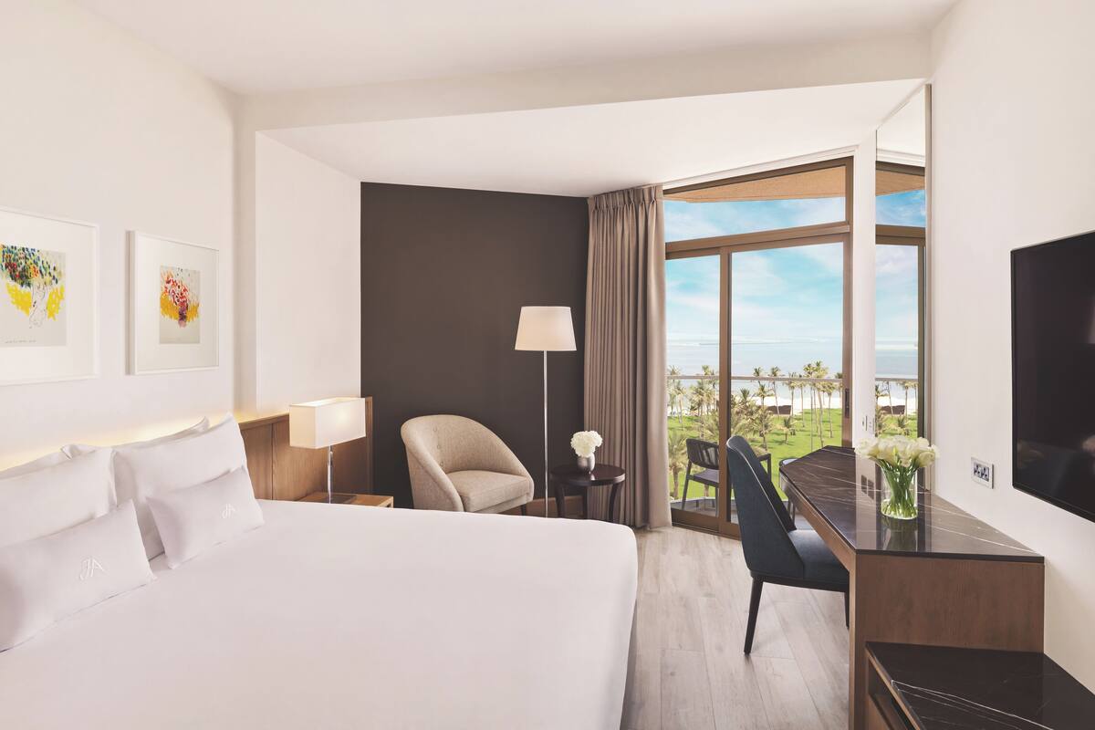 A hotel room with a large bed, a desk with a chair, a TV, and a view of a golf course.
