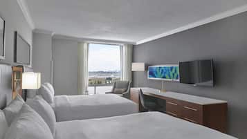 Une chambre d’hôtel avec deux lits, un bureau, une télévision et une vue sur l’aéroport.