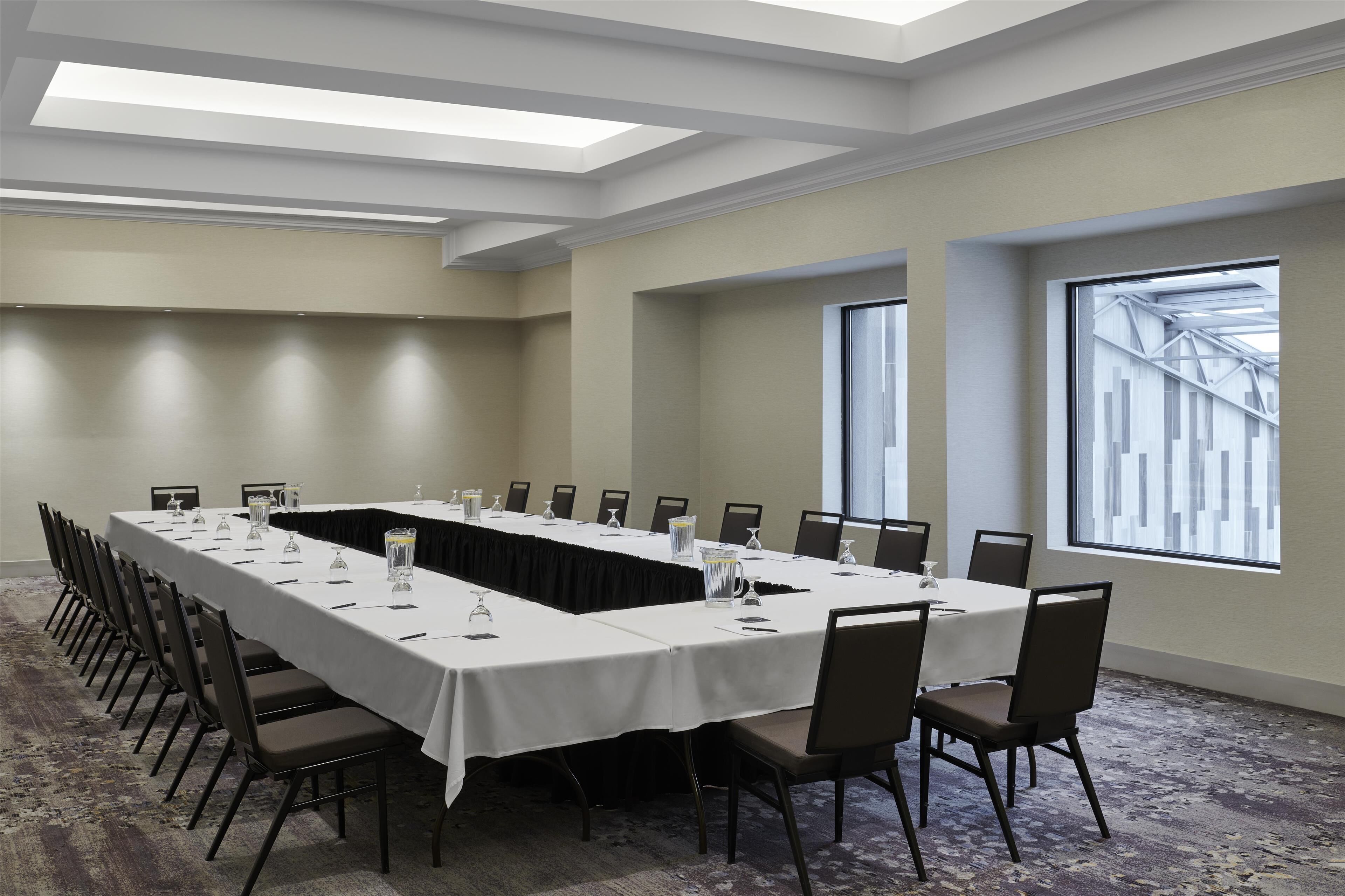 A conference room with a long table, chairs, and large windows.
