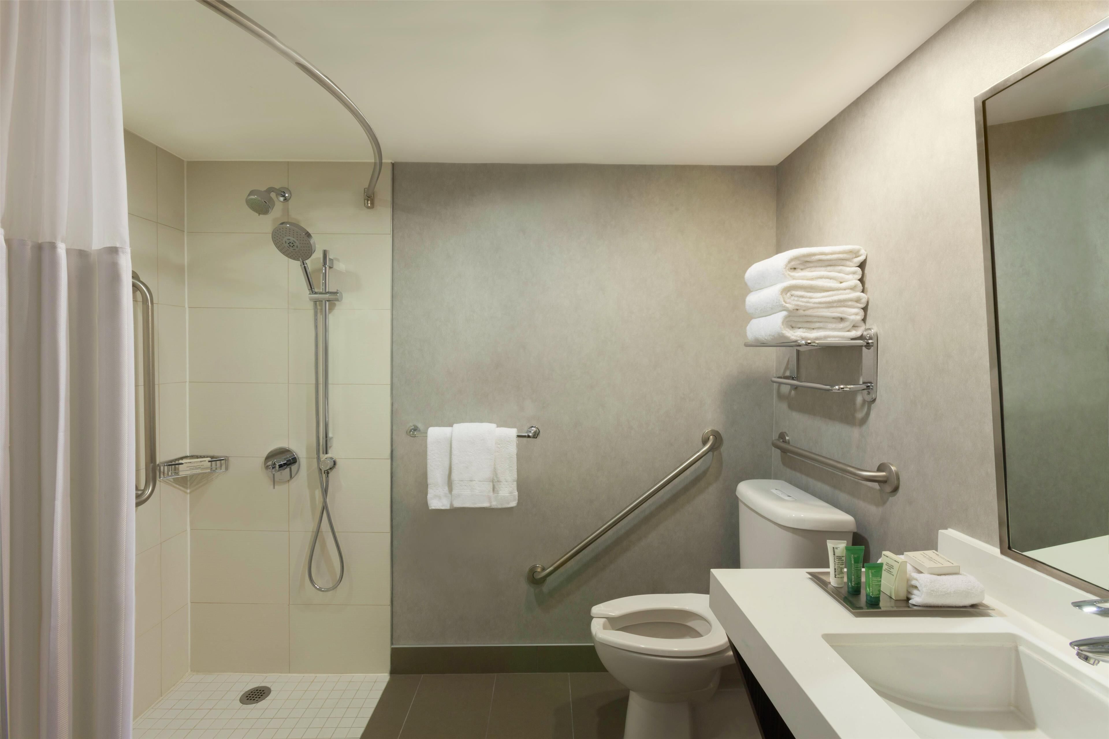 A modern bathroom with a shower, toilet, and sink.