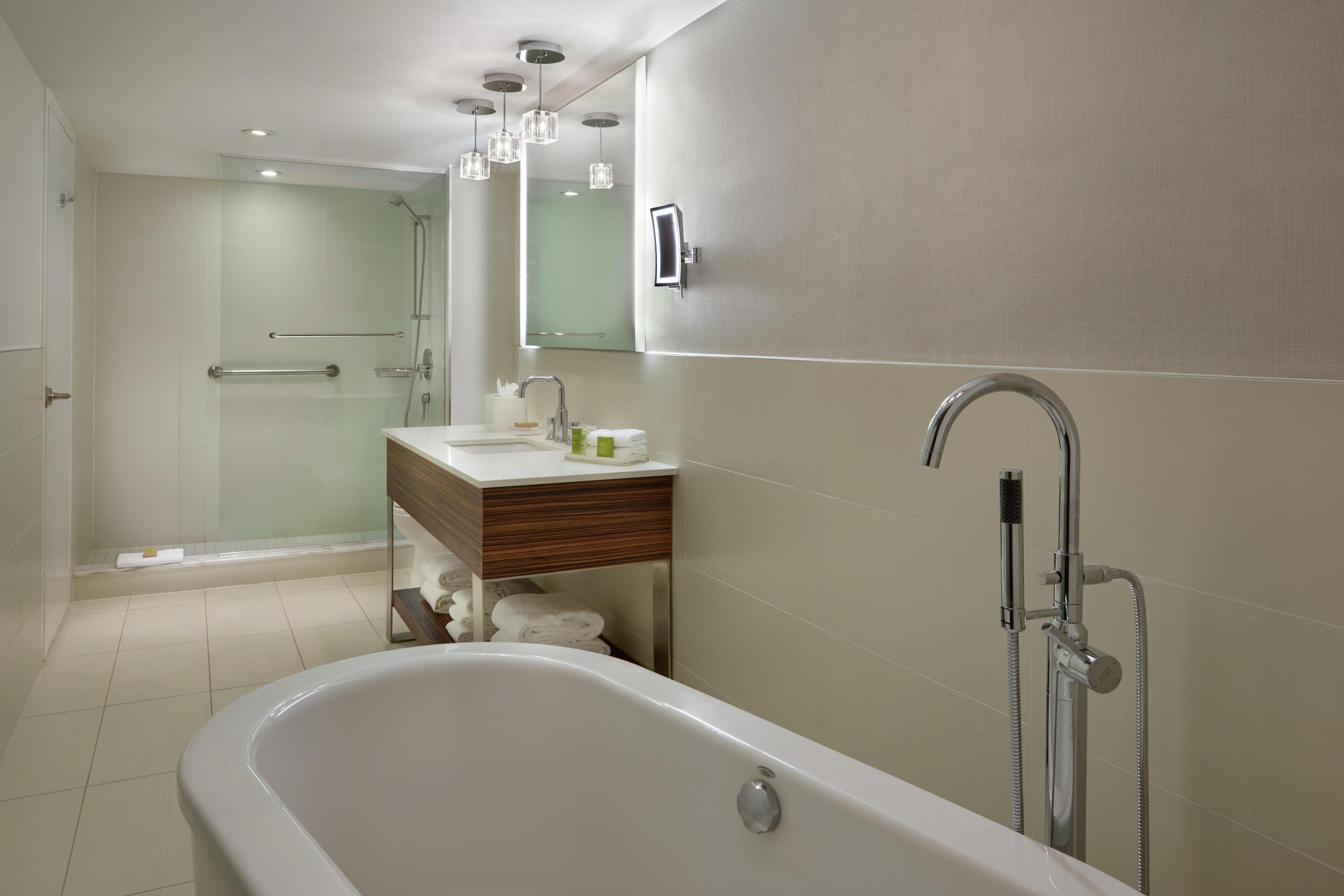 Un baño moderno con bañera, cabina de ducha de vidrio, tocador con espejo y perchero para toallas.