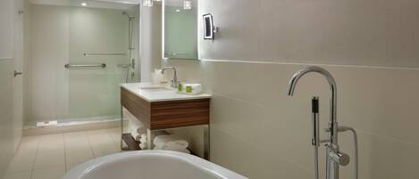 Un baño moderno con bañera, cabina de ducha de vidrio, tocador con espejo y perchero para toallas.