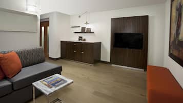 Un salon moderne comprenant un canapé, une table basse, un téléviseur et un meuble en bois intégré.