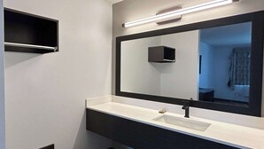 A modern bathroom with a large mirror, a white sink, and a dark vanity. - Motel 6 Lake Elsinore, CA (Lake Elsinore)